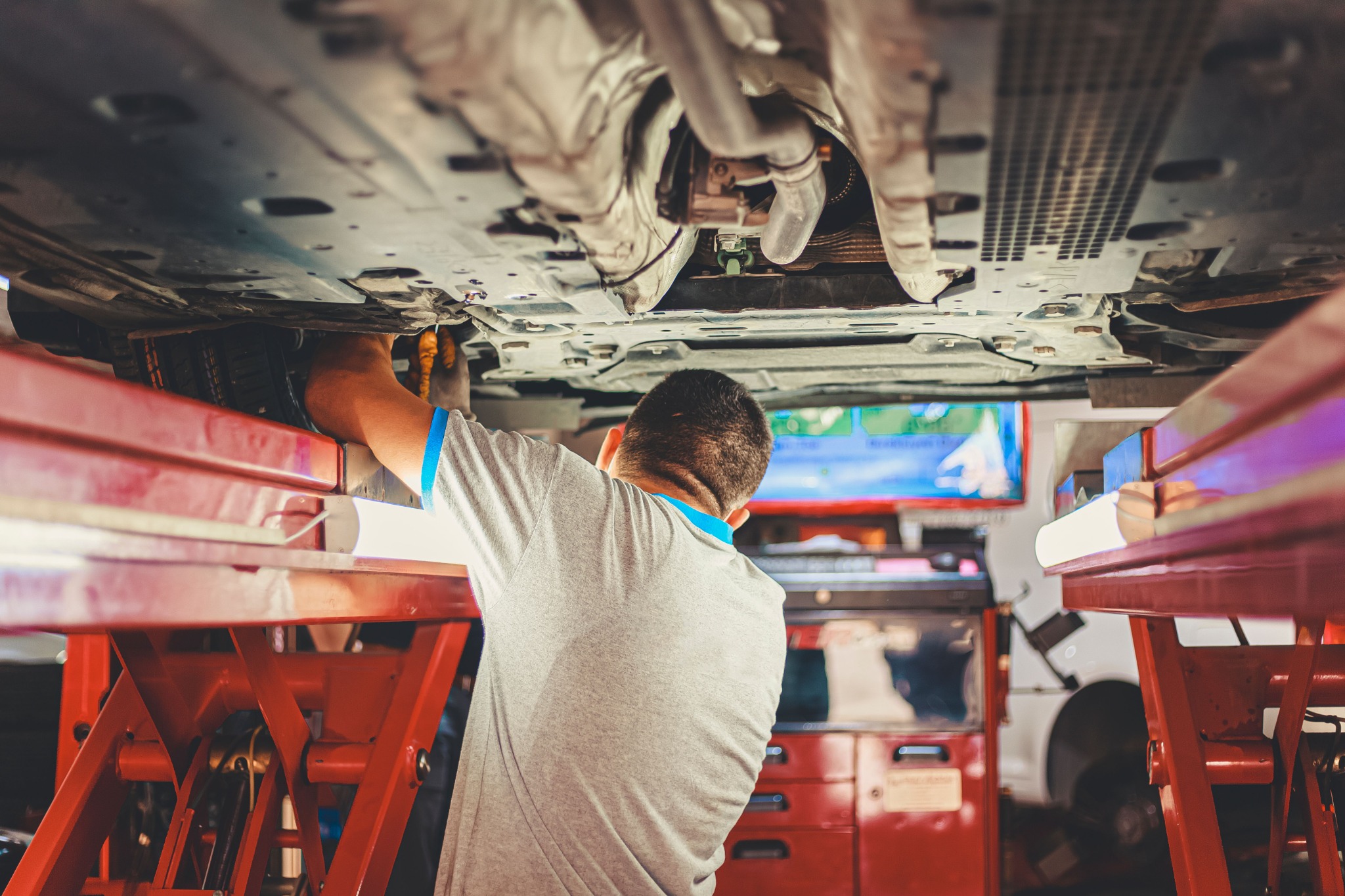 Mechaniker bei Arbeiten an einem Fahrzeug auf einer Hebebühne in einer Kfz-Werkstatt
